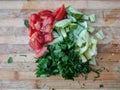 Sliced Ã¢â¬â¹Ã¢â¬â¹tomatoes, bell peppers, dill, parsley and cucumber on a wooden surface, top view. Fresh salad on a cutting board. Royalty Free Stock Photo